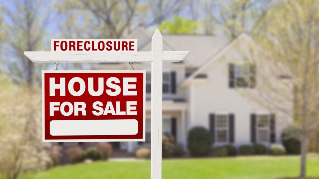 Foreclosure house for sale sign with a home in the background